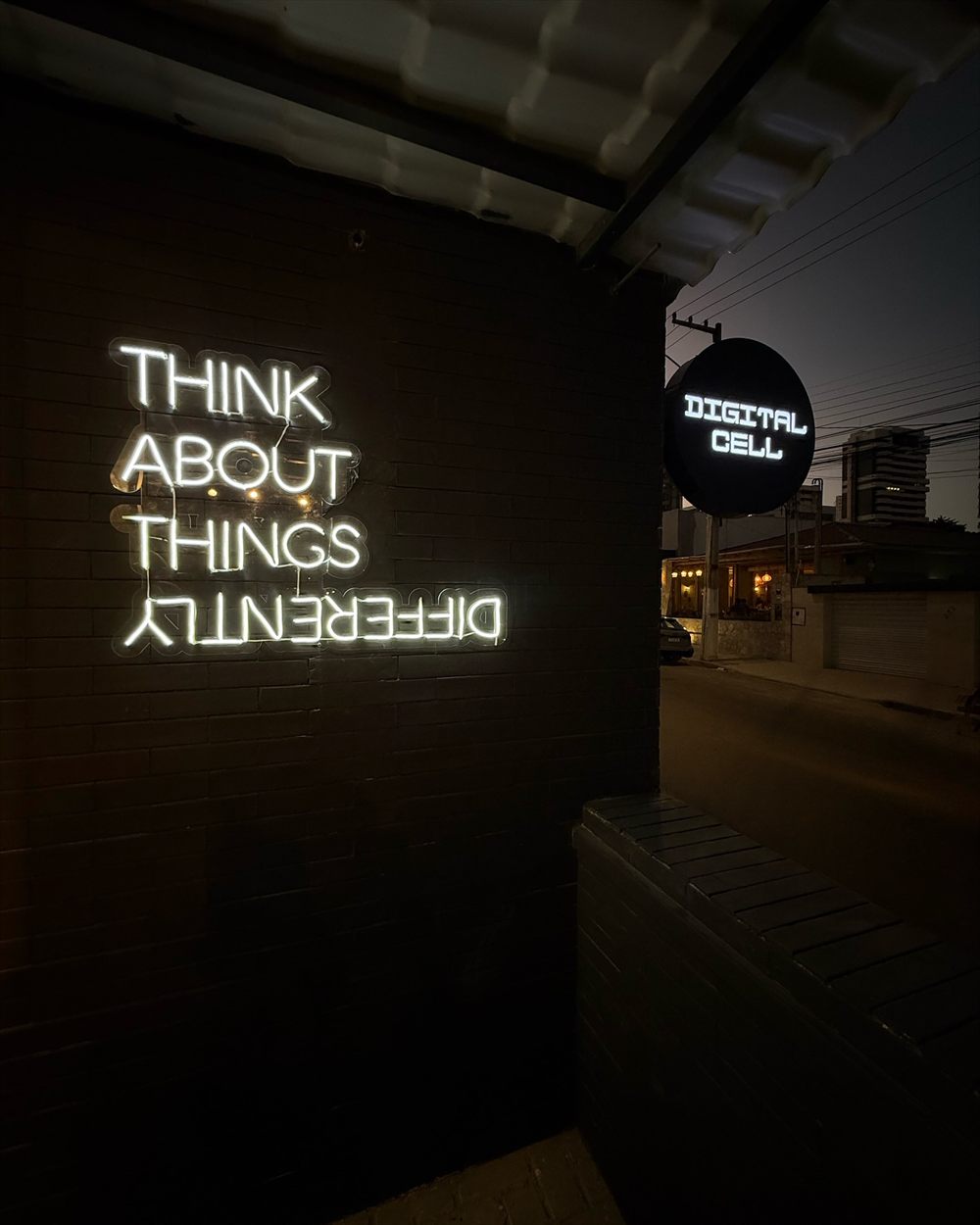 Parede preta da loja com a frase Think about things differently em neon