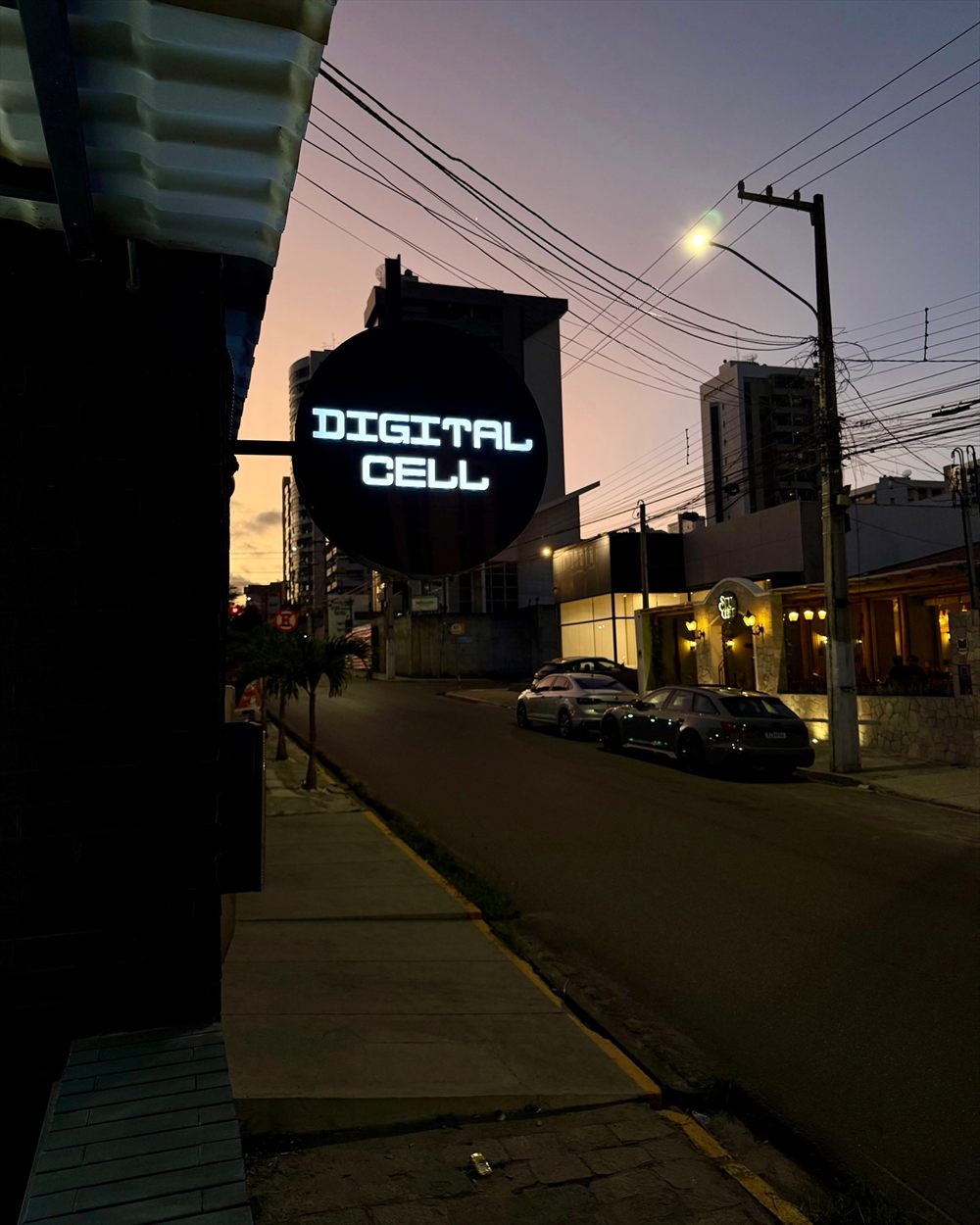 Placa redonda da Digital Cell acesa ao entardecer